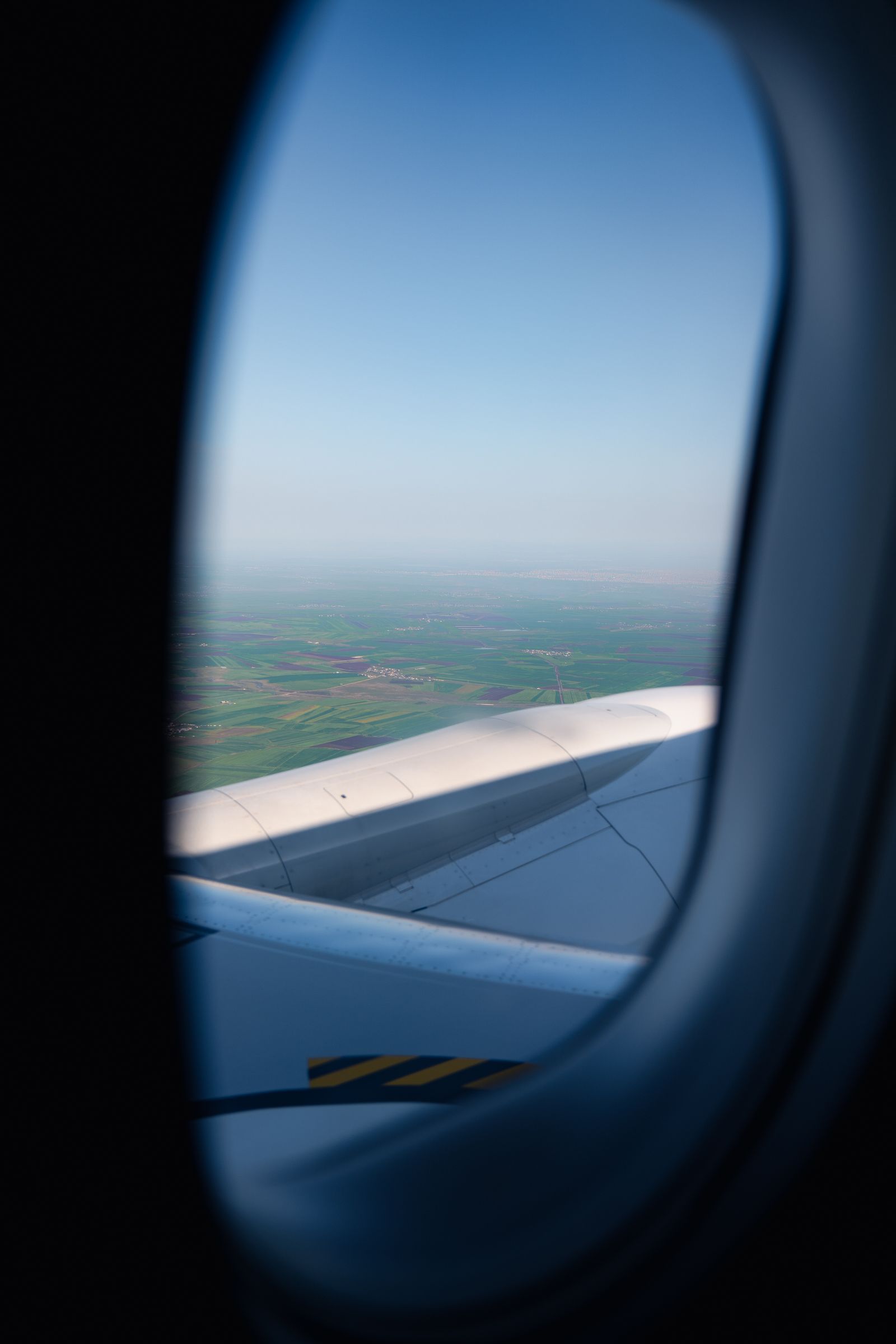 Scenic landscape viewed from an airplane window, representing the journey from the UK to India