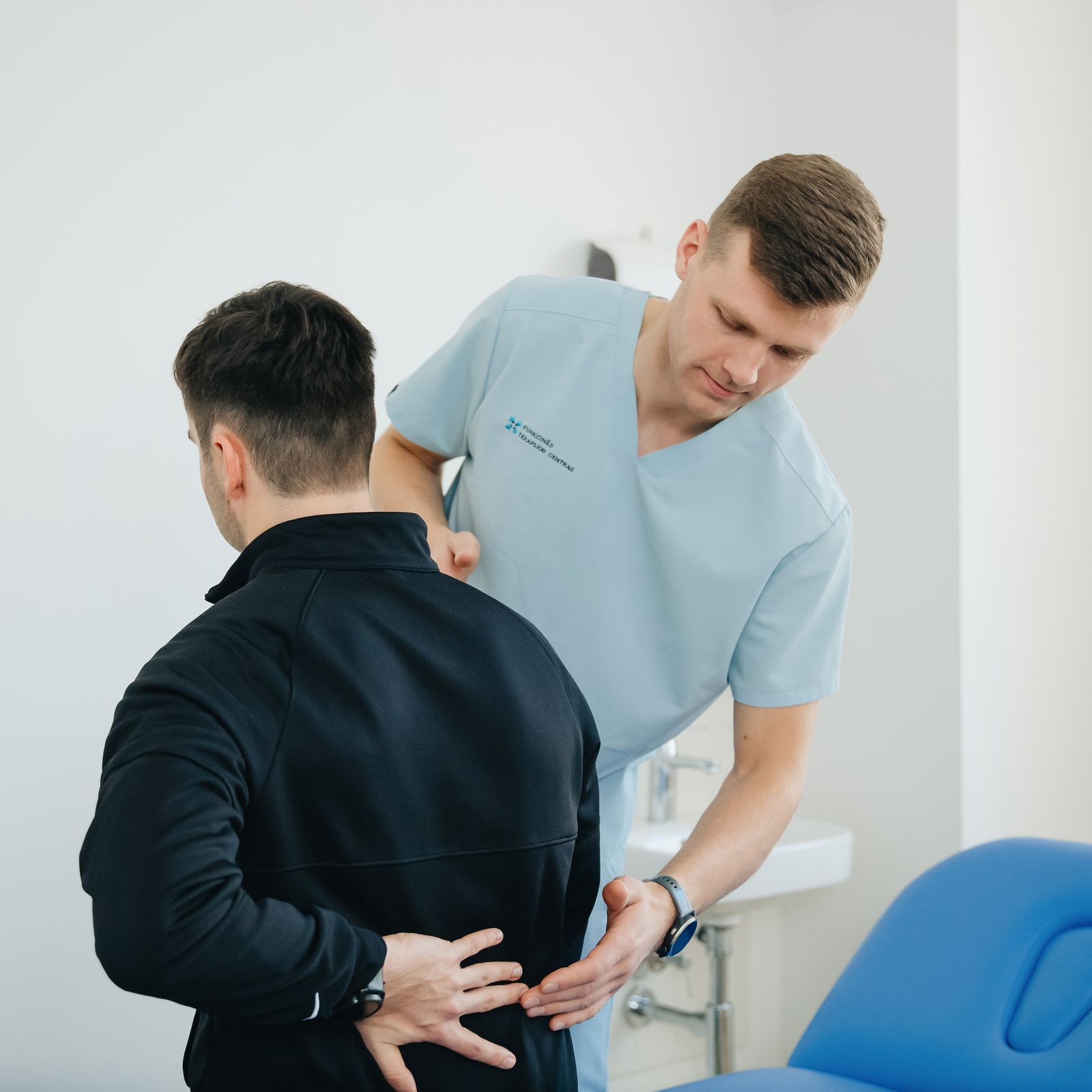 Physiotherapist assisting a patient with back pain in a clinical setting