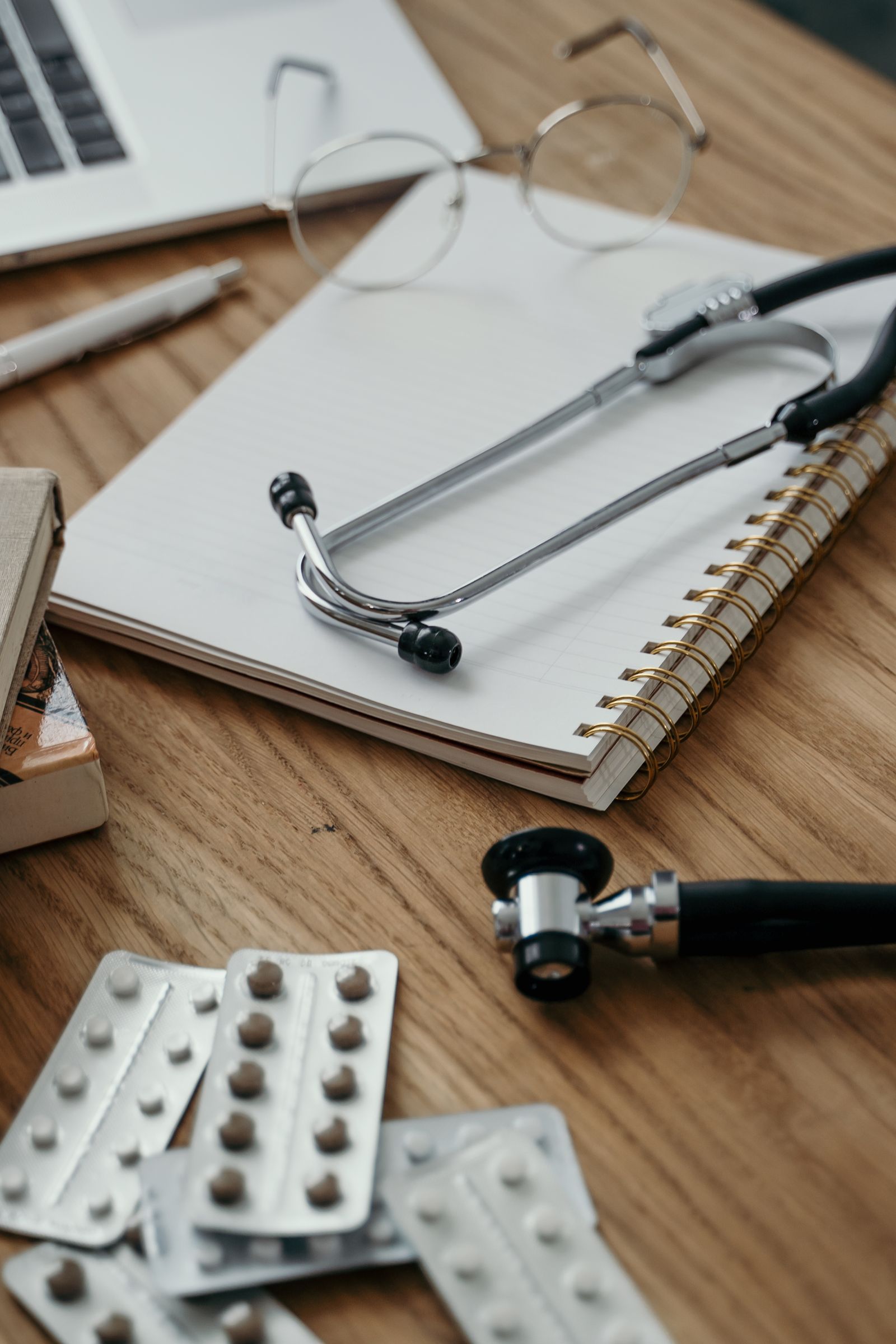 Stethoscope, medication, and notebook on a doctor's desk representing conventional pain treatment