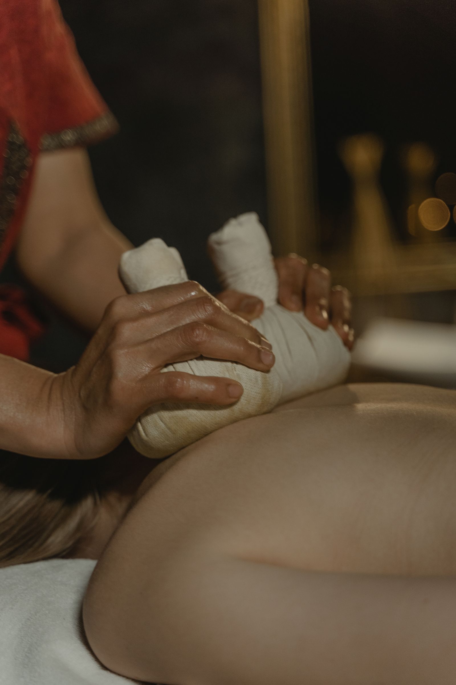 Woman receiving a warm herbal Ayurvedic massage therapy session as part of a Panchakarma program