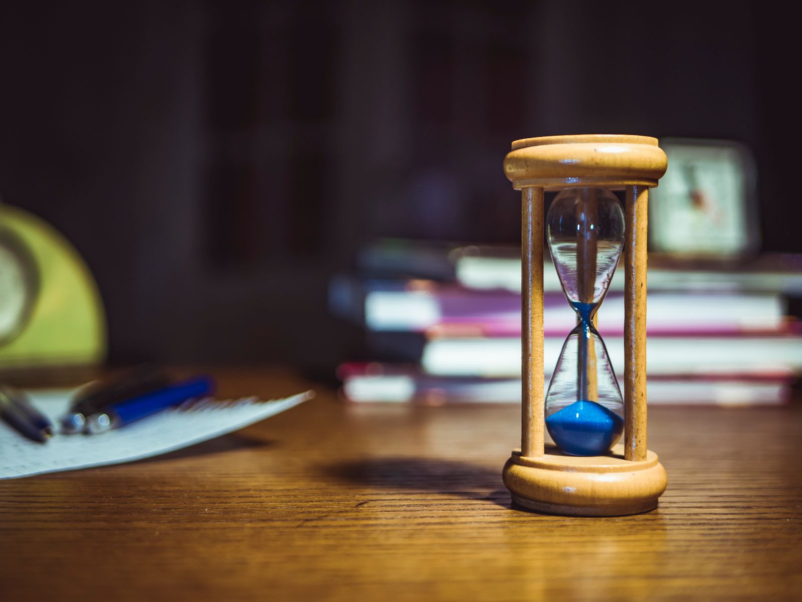 Wooden hourglass on a desk with books, representing the timeline of Ayurvedic treatment results
