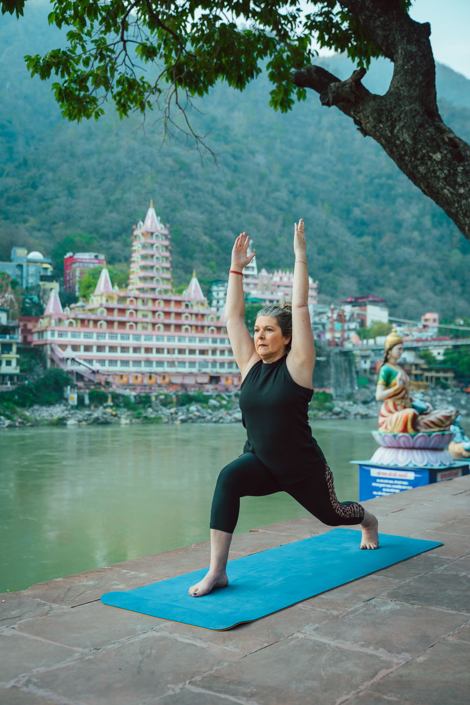 Woman practicing yoga by the Ganges River in Rishikesh, India